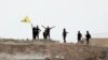 Fighters with the Kurdish People's Protection Units, or YPG, wave their yellow triangular flag on the outskirts of Tal Abyad, Syria, June 15, 2015.