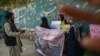 FILE - A member of the Taliban speaks with women protesters as another tries to block the view of the camera with his hand, during a demonstration held outside a school in Kabul, Afghanistan, Sept. 30, 2021.