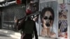 FILE - A Taliban fighter walks past a beauty salon with images of women defaced using spray paint in Shar-e-Naw in Kabul. 