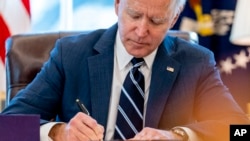 Tổng thống Joe Biden kí thành luật Kế hoạch Giải cứu của Mỹ, một dự luật cứu trợ đại dịch COVID-19, trong Phòng Bầu dục Nhà Trắng, ngày 11 tháng 3, 2021.