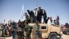 In this photo taken on June 17, 2018, Afghan Taliban militants and residents stand on a armoured Humvee vehicle of the Afghan National Army (ANA) as they celebrate a ceasefire on the third day of Eid in Maiwand district of Kandahar province.